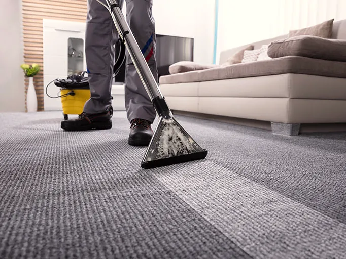 Carpet cleaning wand leaving a clean stripe across gray carpet next to a sofa